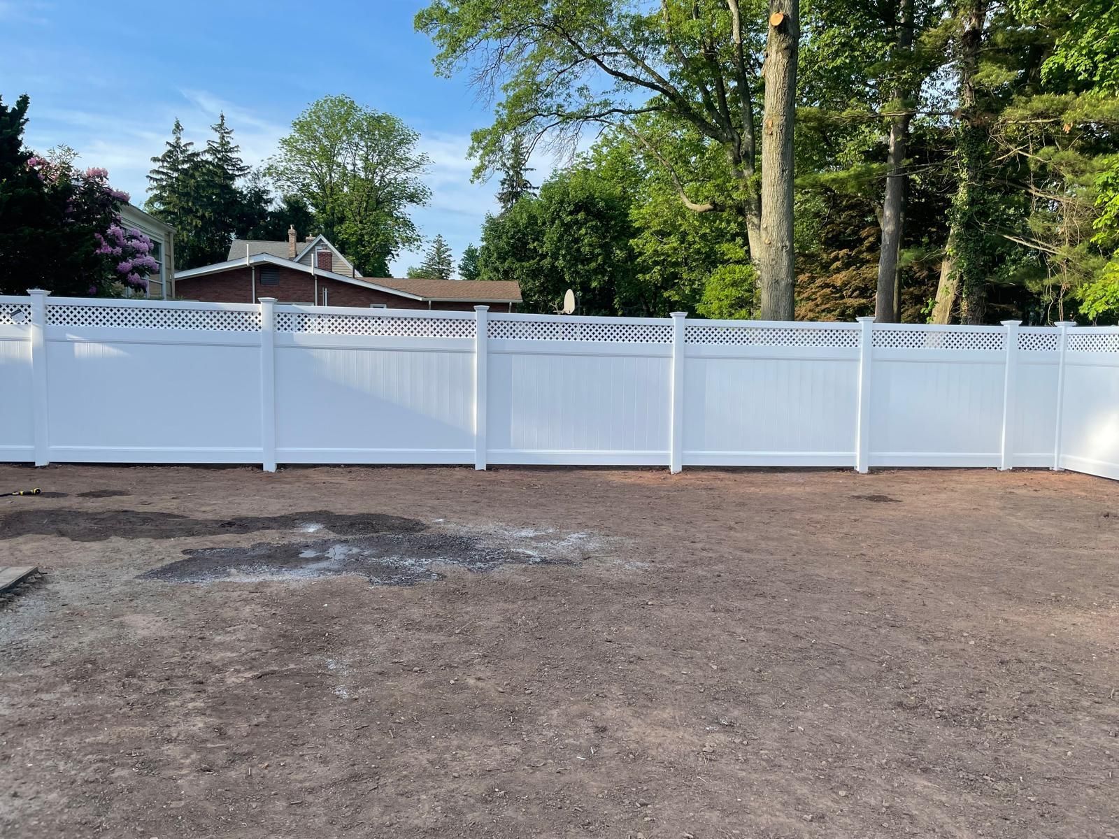 A white fence is sitting in the middle of a dirt field.