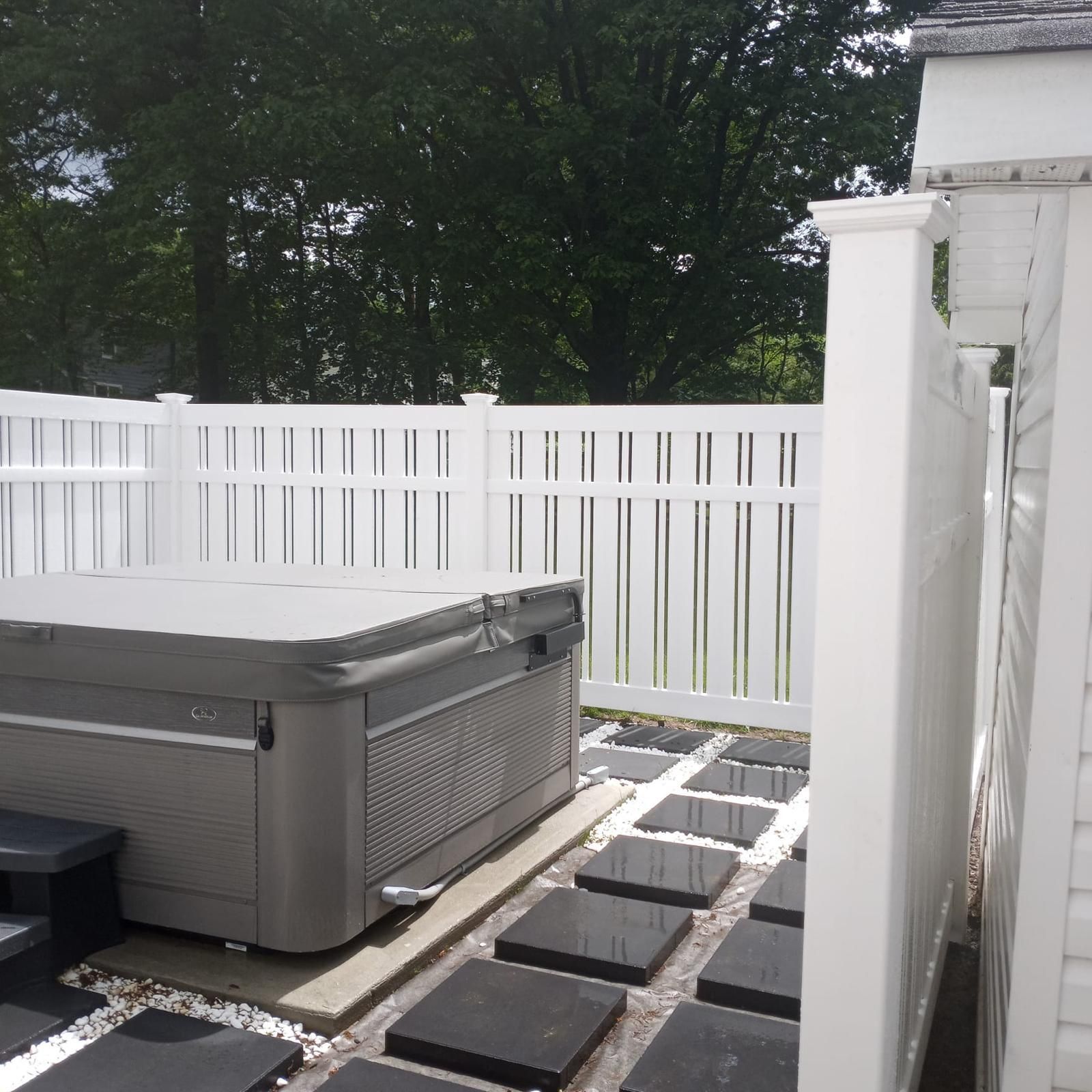 A hot tub with a white fence behind it