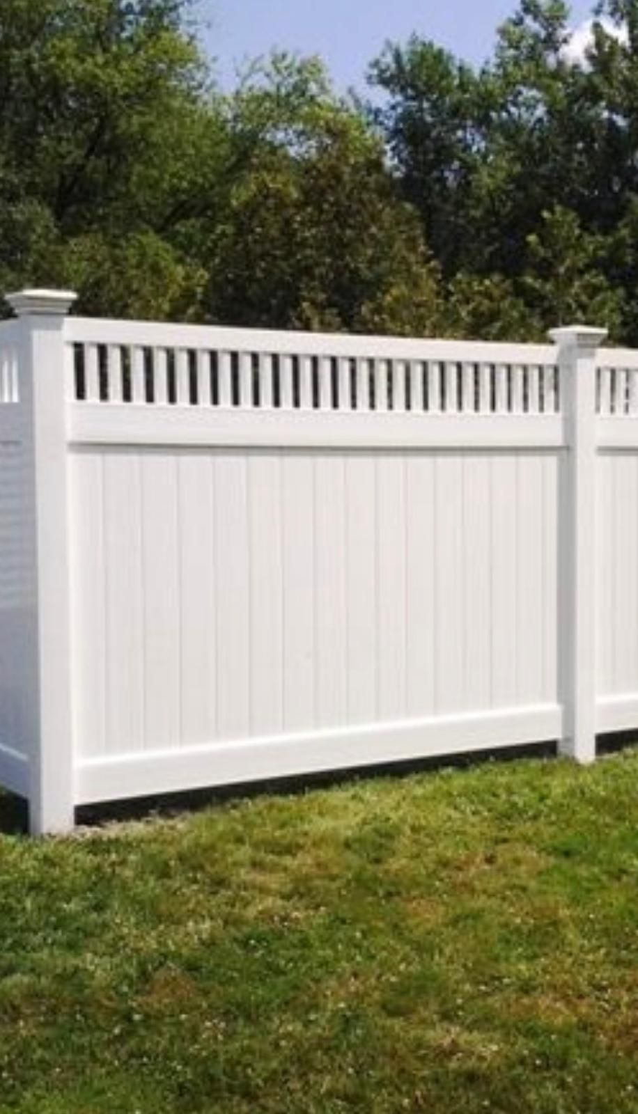 A white fence is sitting in the middle of a lush green field.