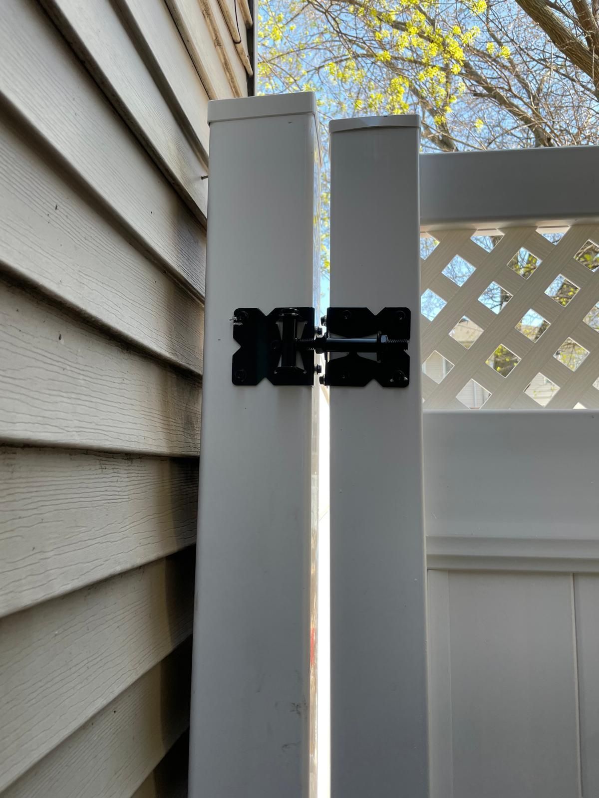 A white fence with a black x on it is next to a white house.