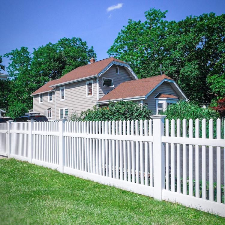 A white picket fence surrounds a house with a red roof