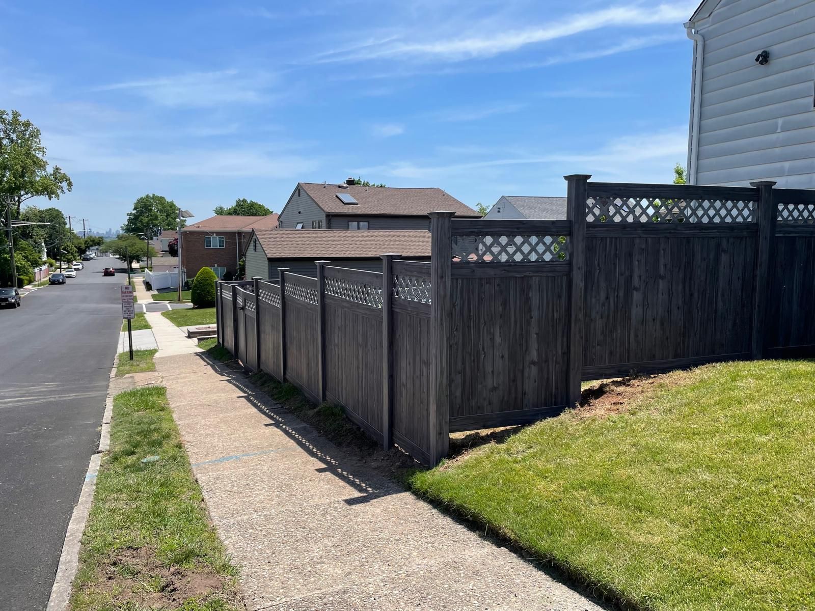 A wooden fence along a sidewalk in a residential neighborhood.
