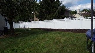 A white fence in the backyard of a house