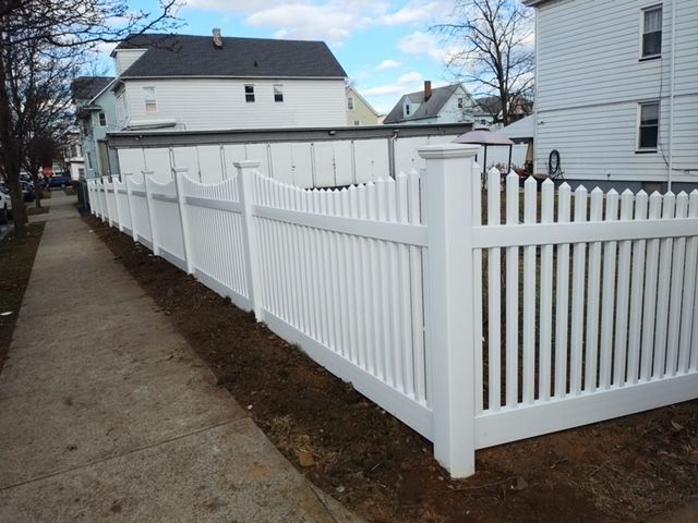 A white picket fence along a sidewalk next to a house