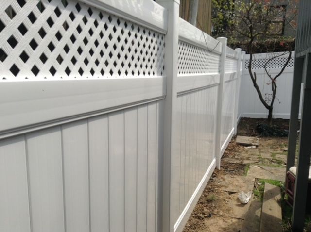 A white fence with a black lattice on the top of it.