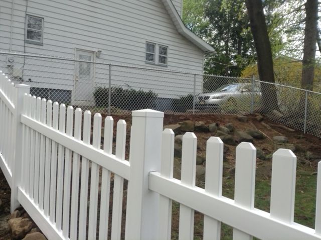 A white picket fence is in front of a white house