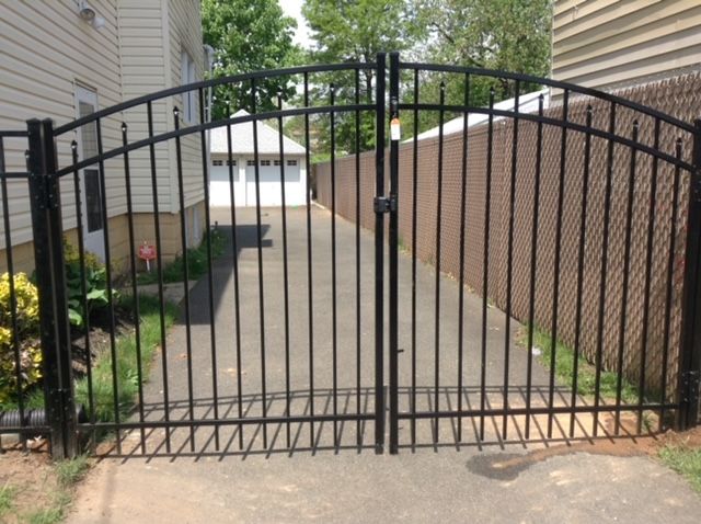 A black wrought iron gate leading to a driveway