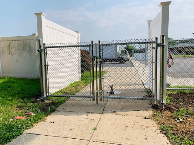 A chain link fence is being installed on a sidewalk