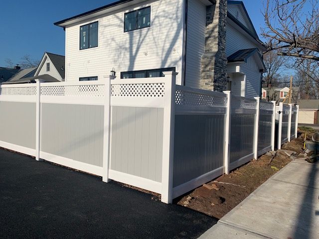 A white fence is sitting in front of a white house.