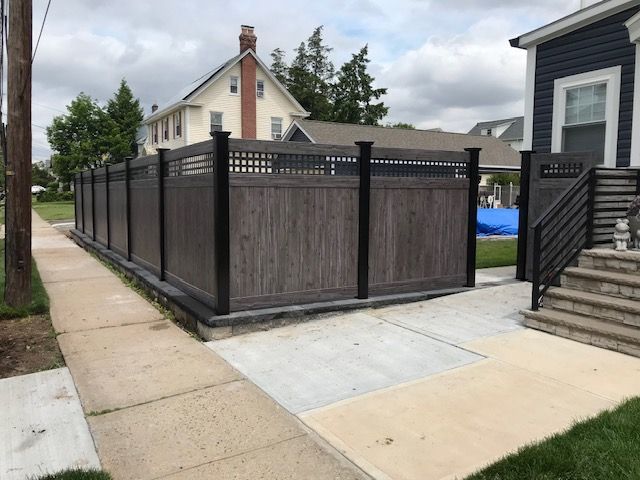 A wooden fence along a sidewalk next to a house