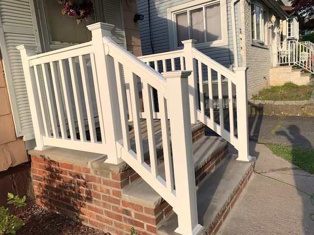 A white railing on a brick porch of a house