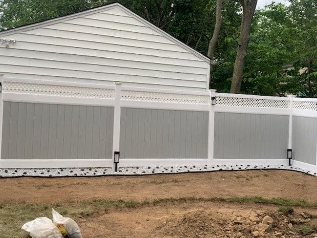 A white house with a gray and white fence in front of it.