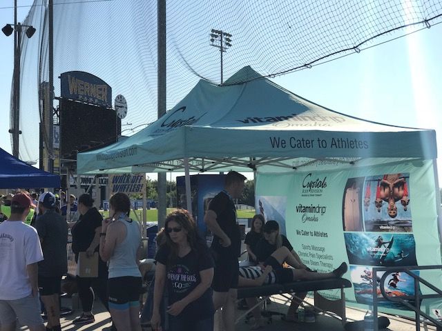 Crowded outdoor event with a blue tent, people walking, and a large water-themed banner.