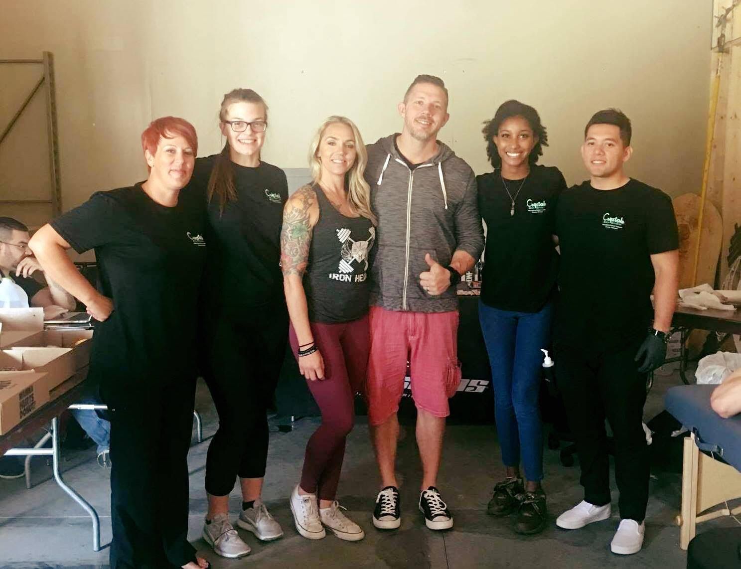 Six people standing together indoors, smiling at the camera in a casual group photo.