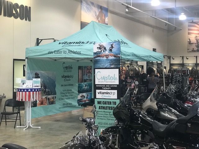 Motorcycle expo booth with a teal canopy and rows of motorcycles inside a convention hall