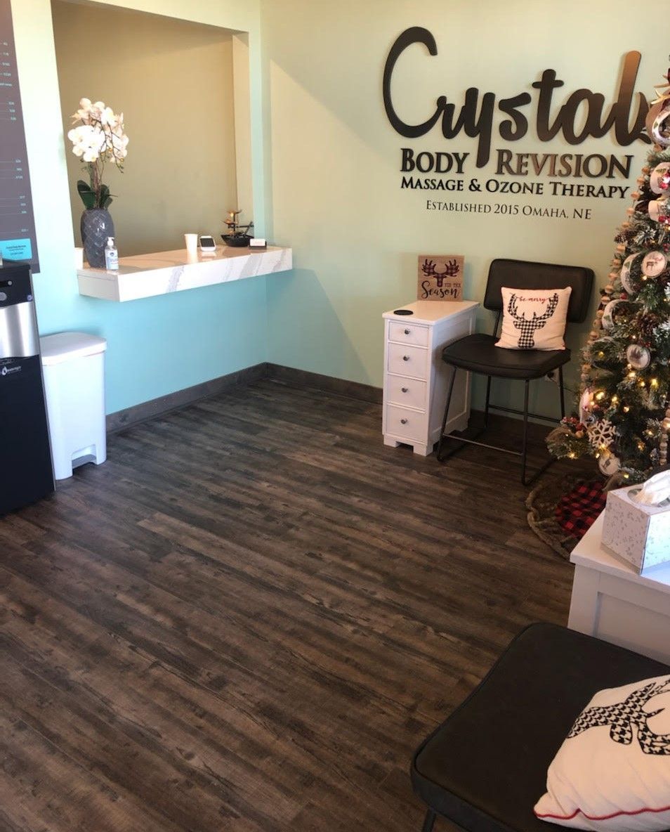 Reception area of Crystal Body Revision with white desk, chair, decor, and wood-look flooring