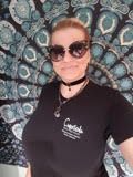 Person wearing sunglasses and a black polo shirt, posing in front of a patterned backdrop.