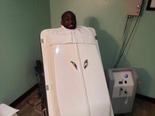 Person standing in a white medical imaging machine in a clinic room
