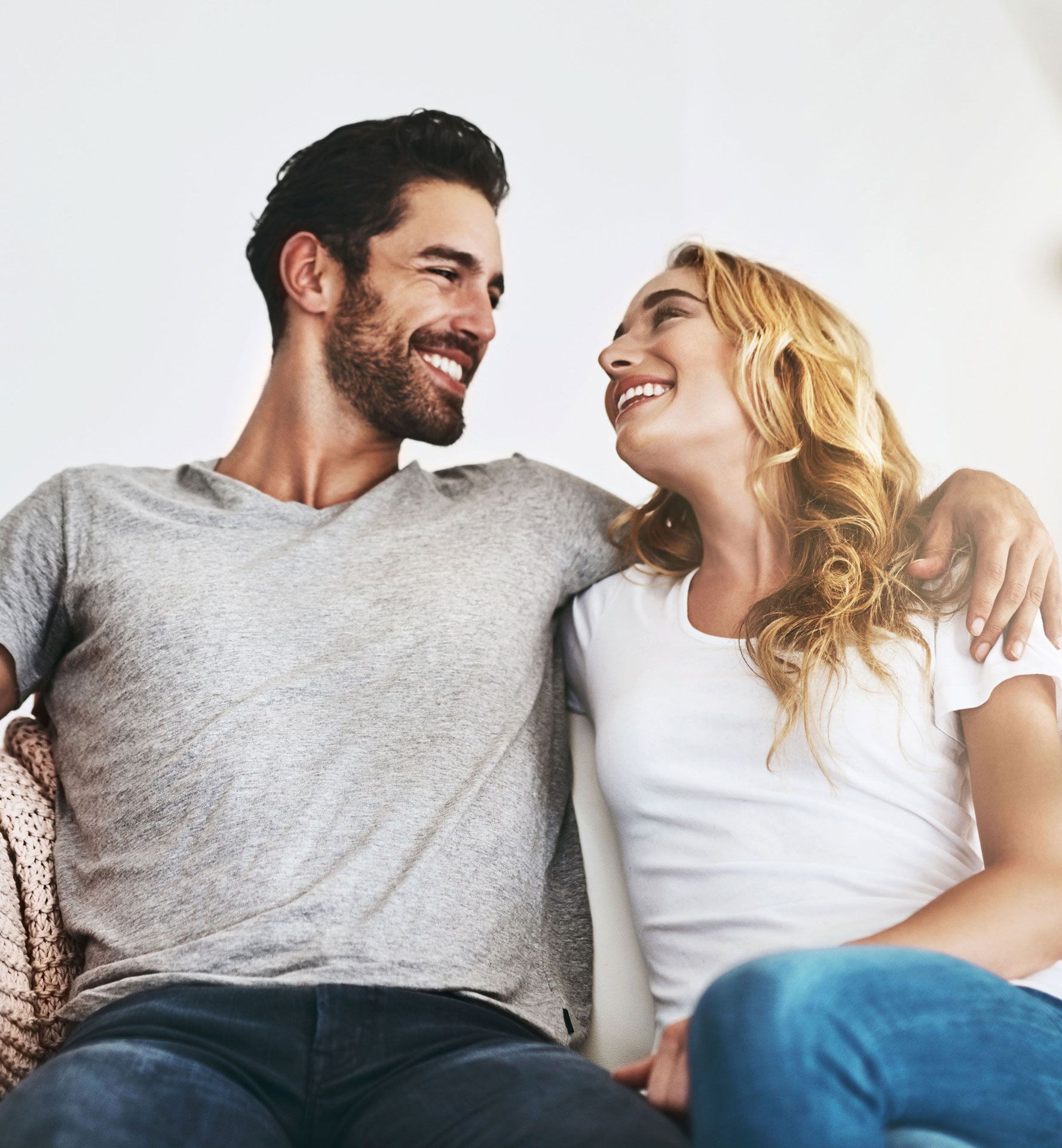 Man with arm around woman, smiling at each other.
