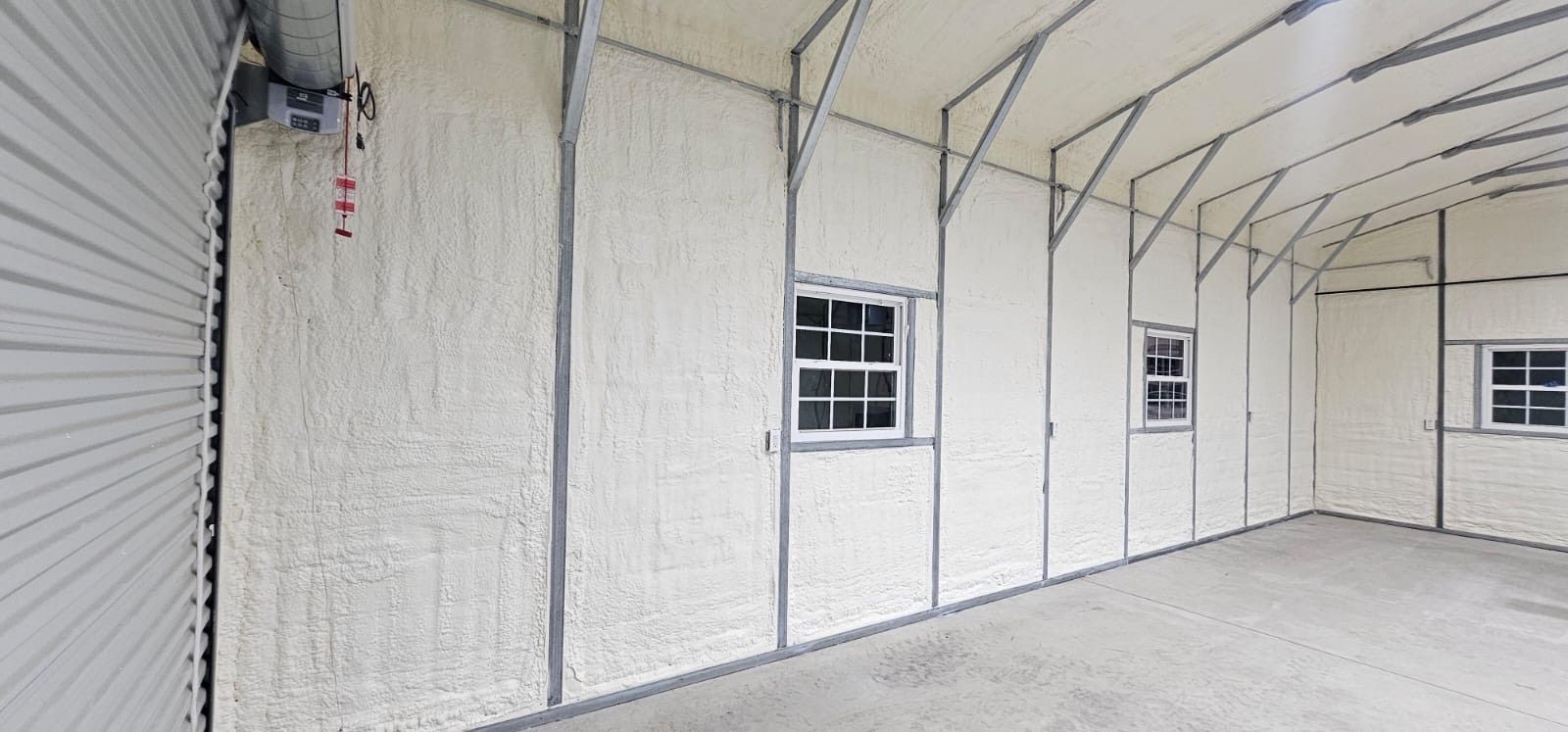 A large empty garage with white walls and windows.