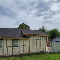 A small house with a roof is sitting in the middle of a grassy field.
