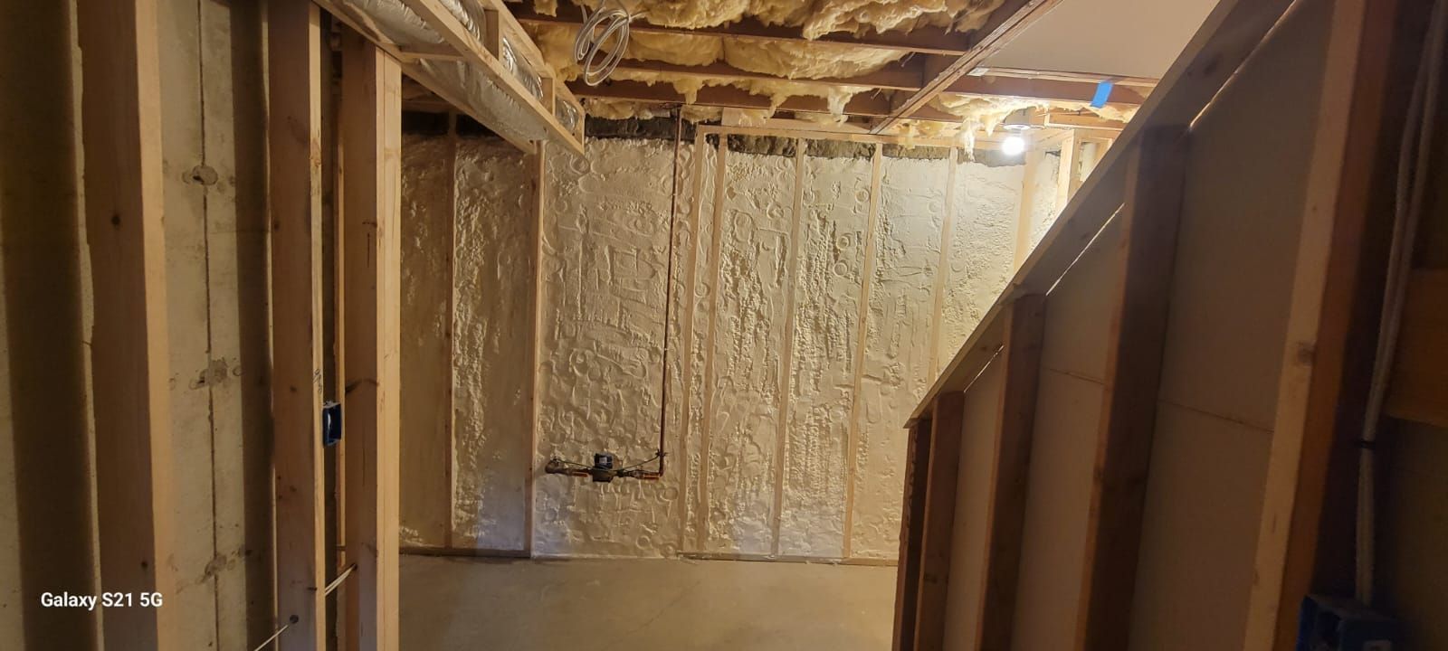 A basement under construction with foam insulation on the walls and ceiling.