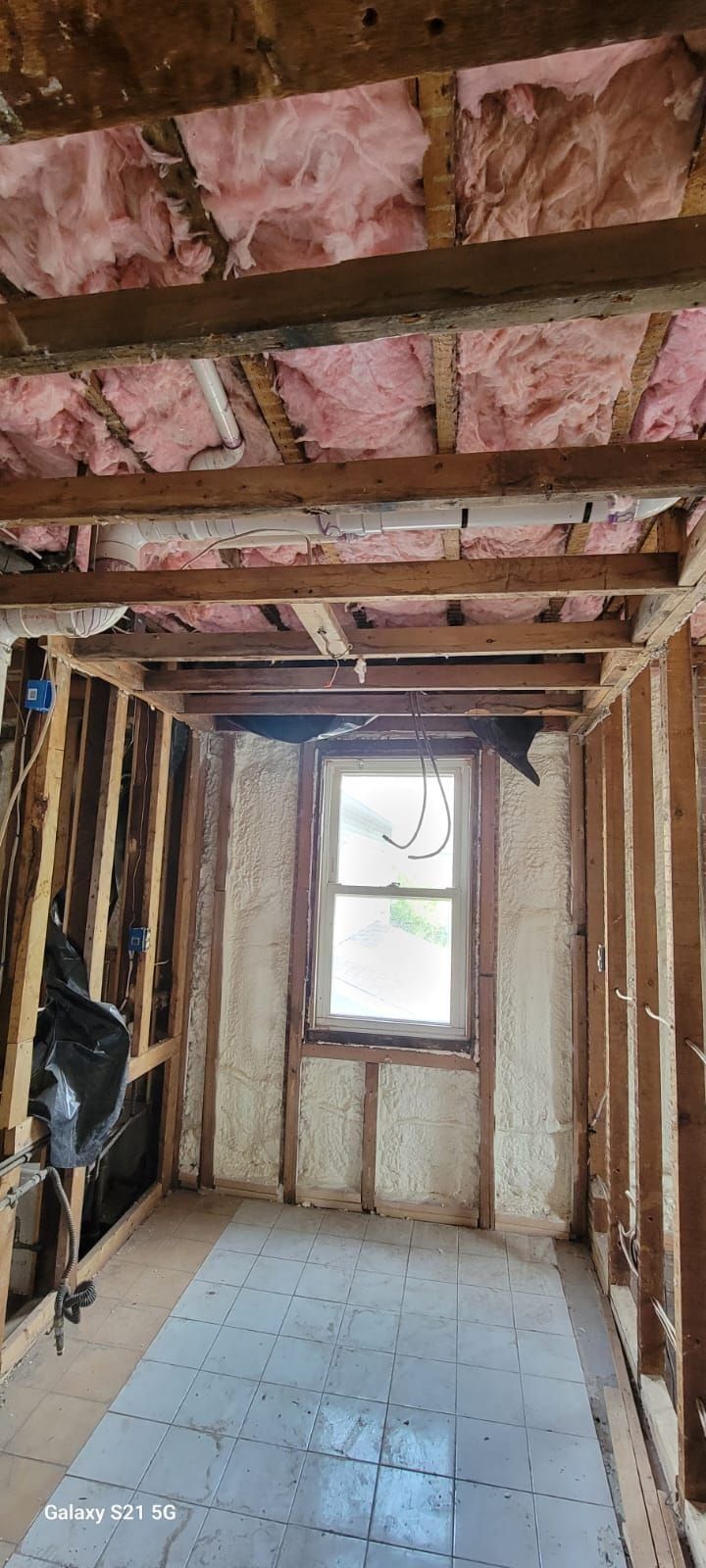 A room with insulation on the walls and ceiling and a window.