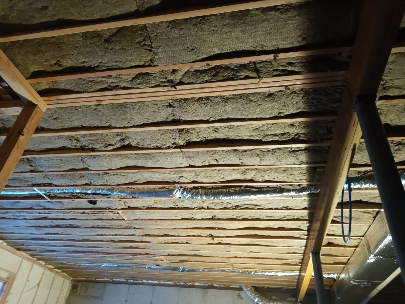 A ceiling with a lot of wooden beams and pipes