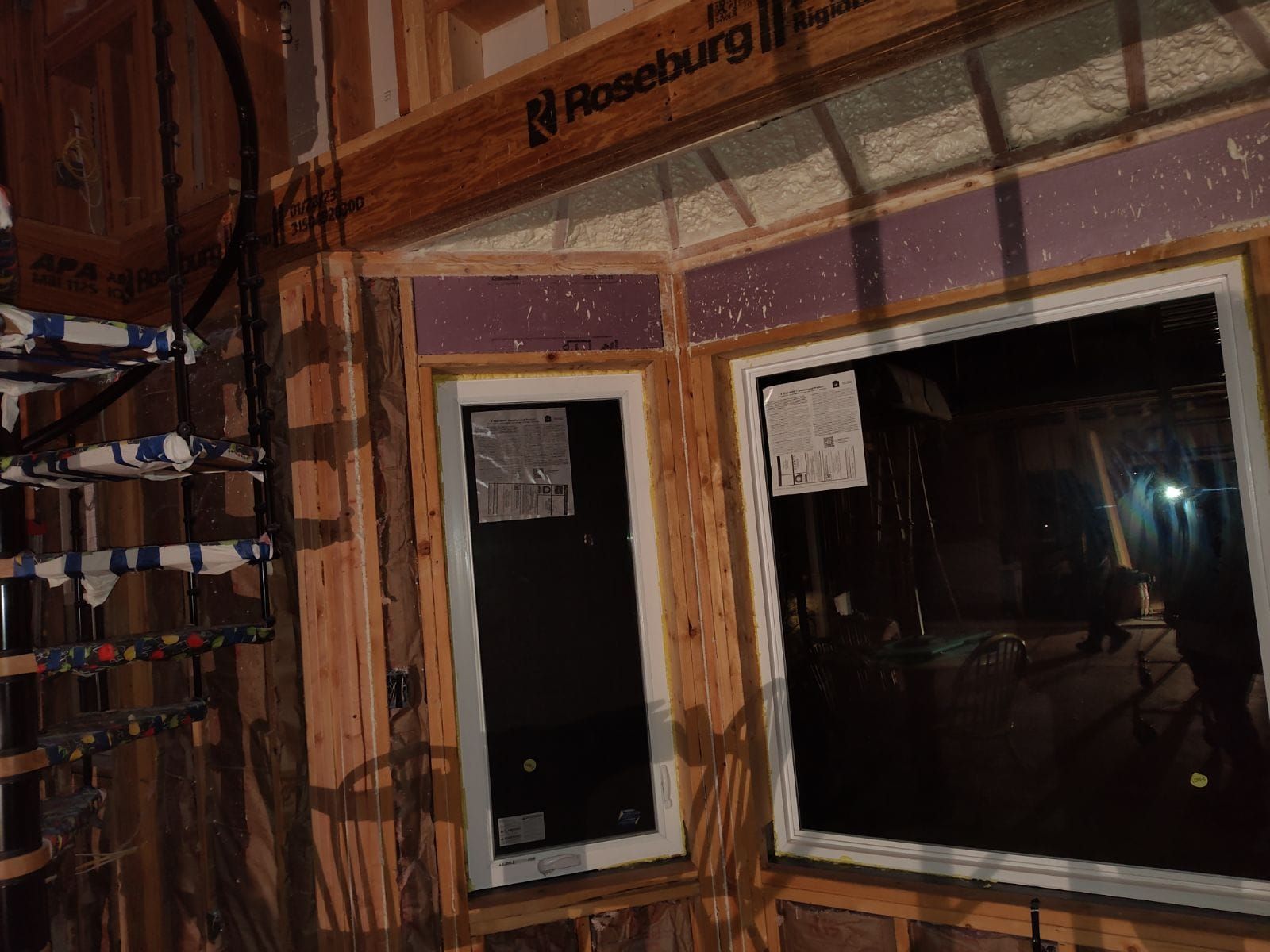 Two windows are being installed in a house under construction.