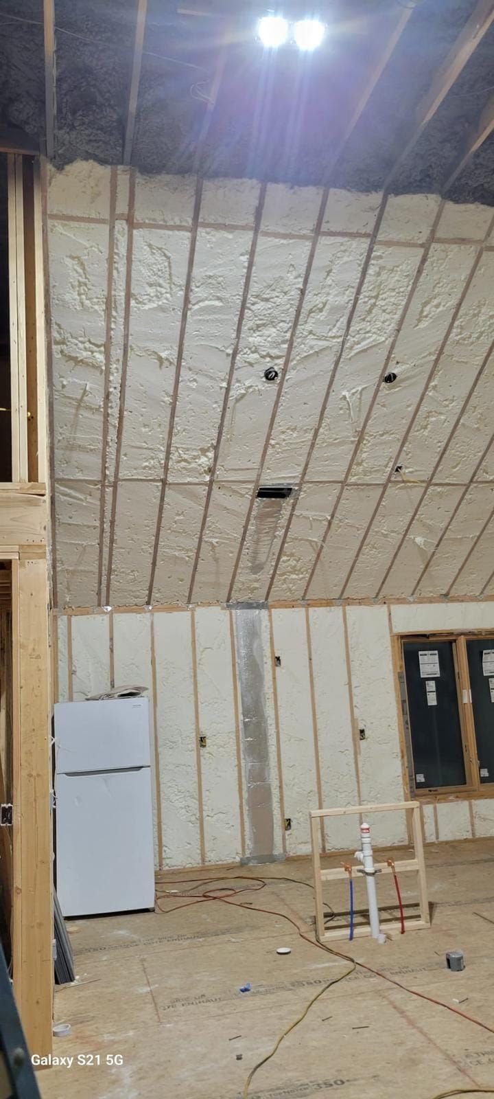 A room with a refrigerator and a ceiling that is insulated.