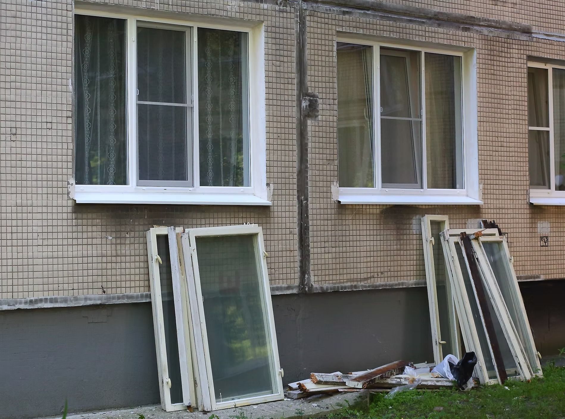 Windows and window frames leaning against a brick building under renovation