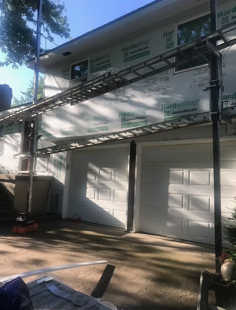 Sunlit white building with two closed garage-style doors and a metal awning in front