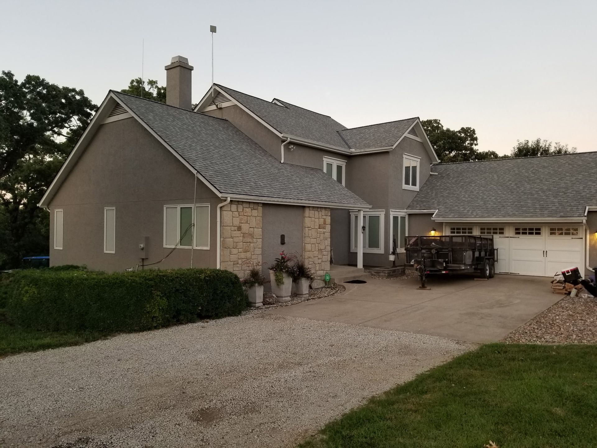 Suburban house with stone facade, gravel driveway, and garage at dusk