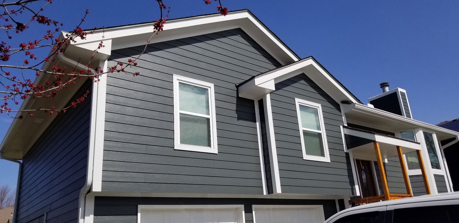 Gray house with white trim and porch under a clear blue sky