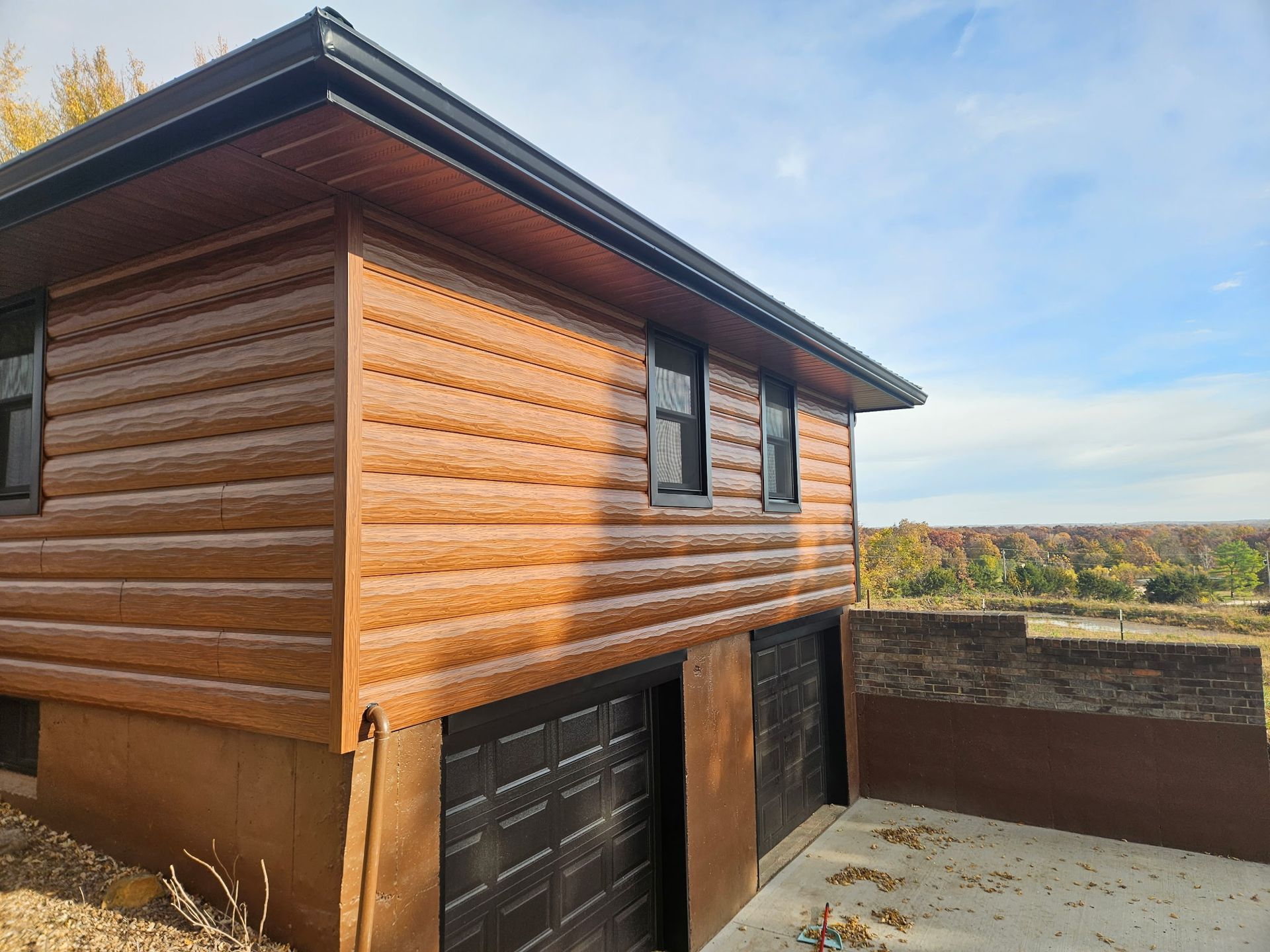 Wooden house with a garage, viewed from the corner against a cloudy sky
