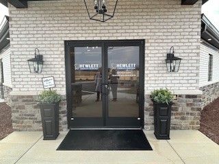 A brick building with a glass door and planters in front of it