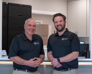 Two men are standing next to each other in a room and smiling
