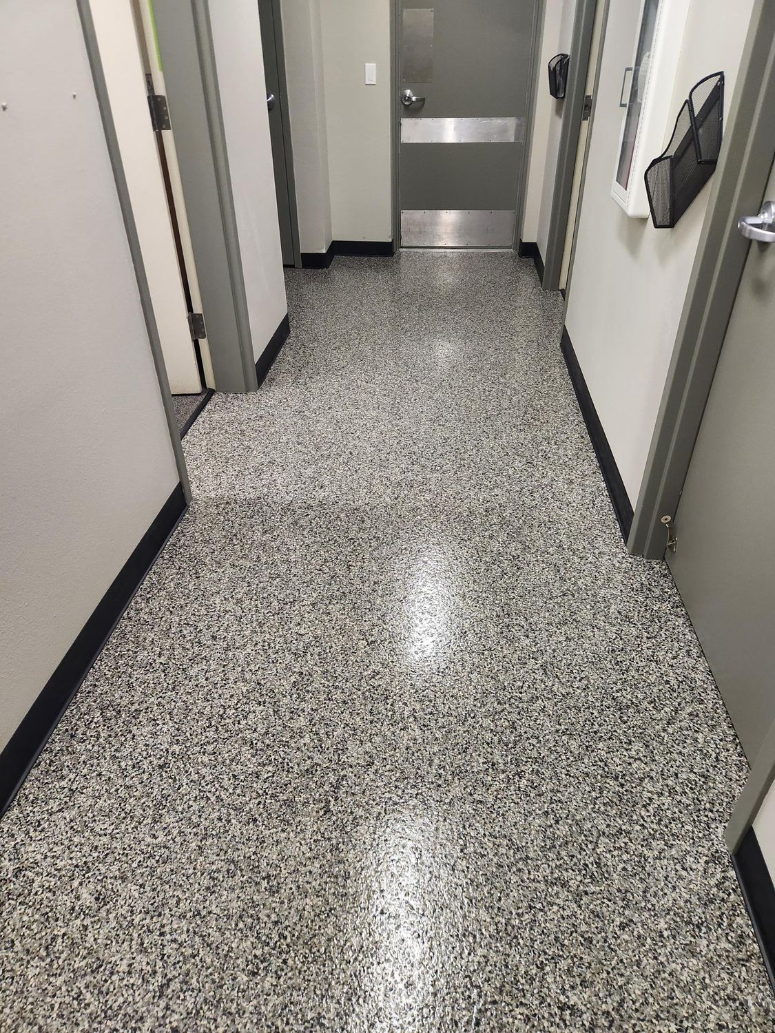 A hallway with a concrete floor and a door in a building.