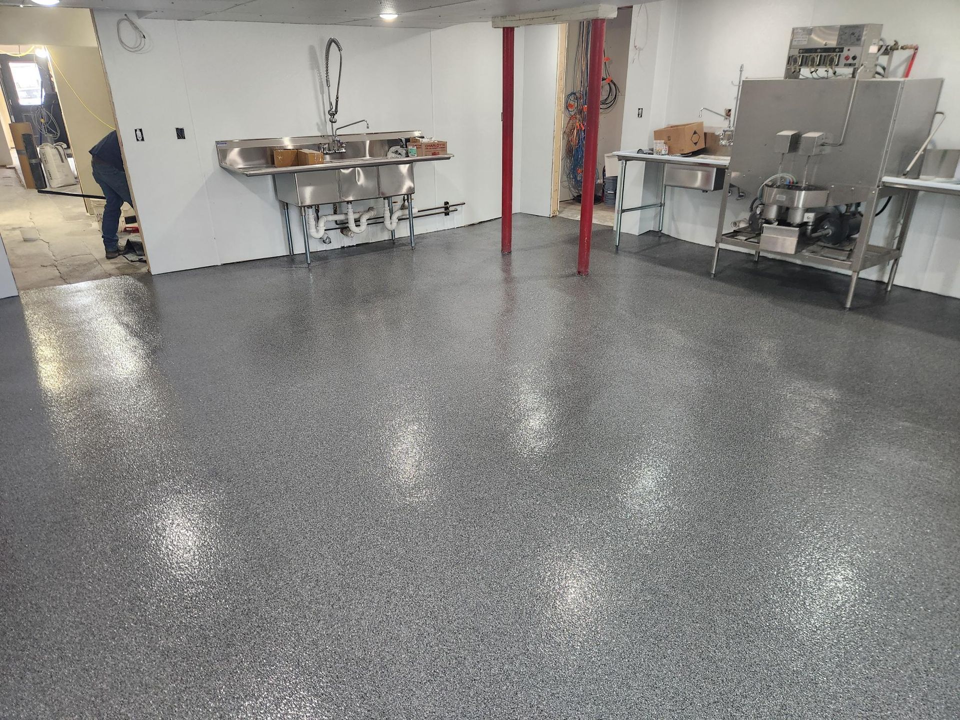 A kitchen with a gray floor and stainless steel sinks.