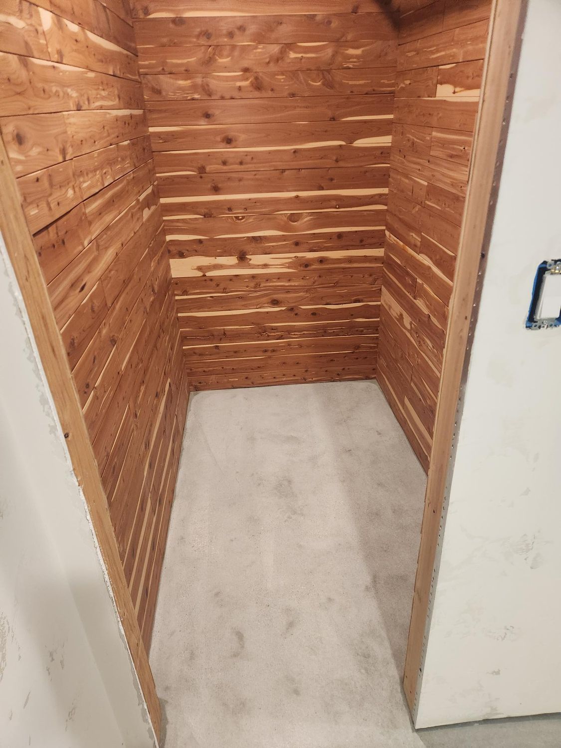 A small room with wooden walls and a white door.