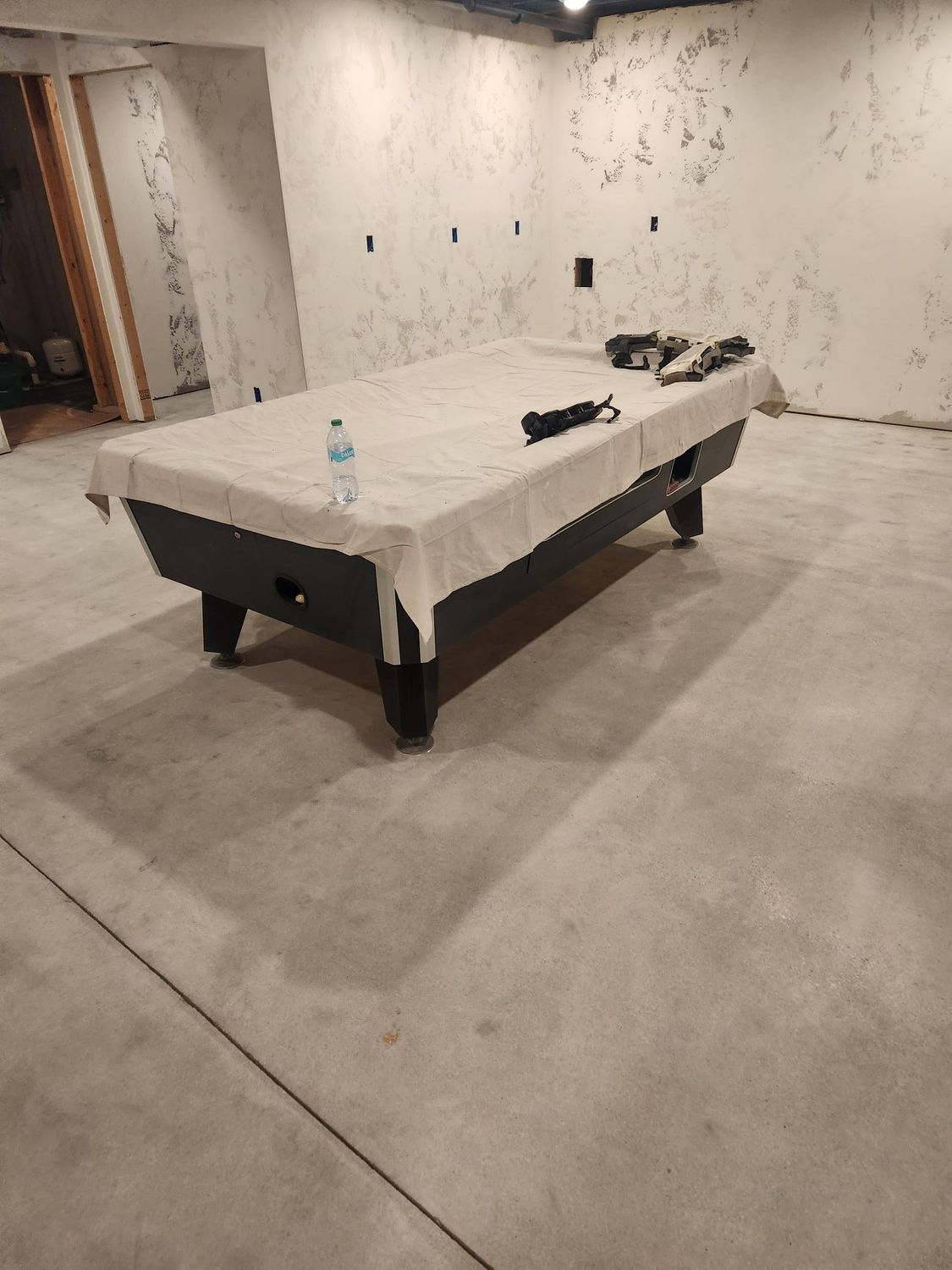 A pool table is sitting on a concrete floor in a basement.