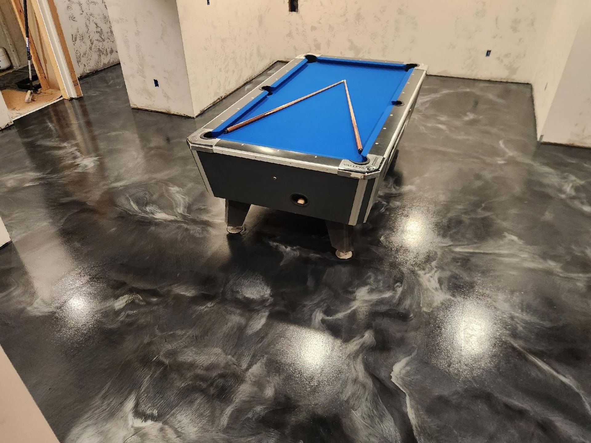 A pool table is sitting on a black and white marble floor.
