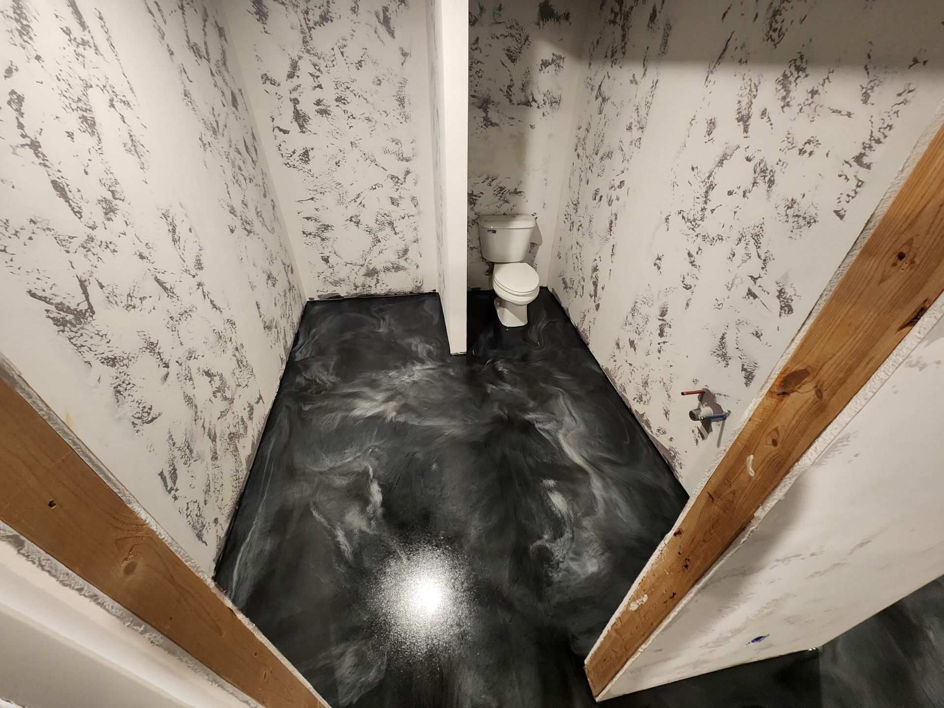 A bathroom with a toilet and a black floor