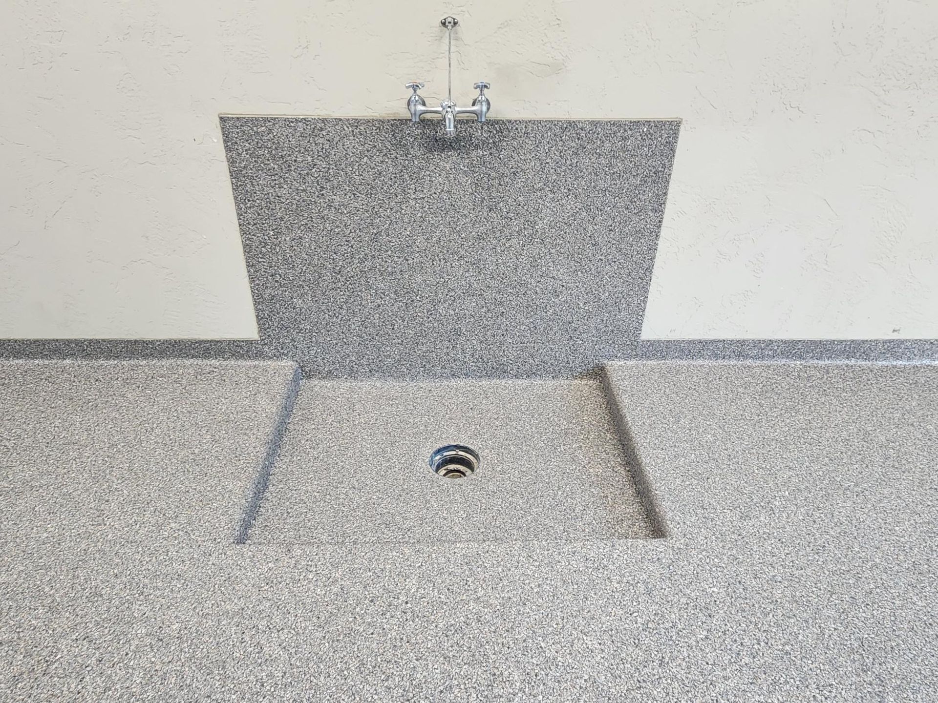 A bathroom sink with a drain in the floor.