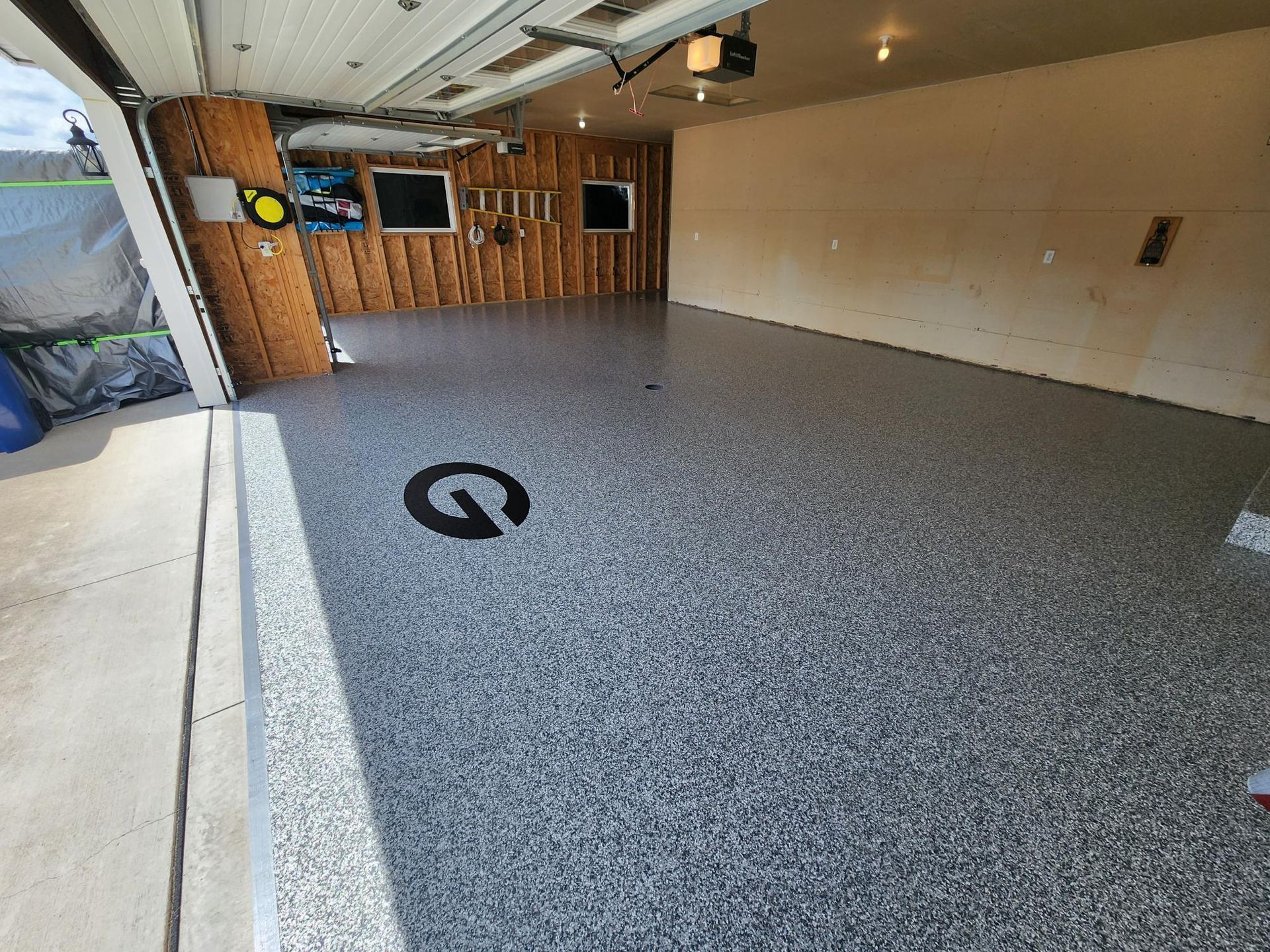 A garage with a gray floor and a black g on it.