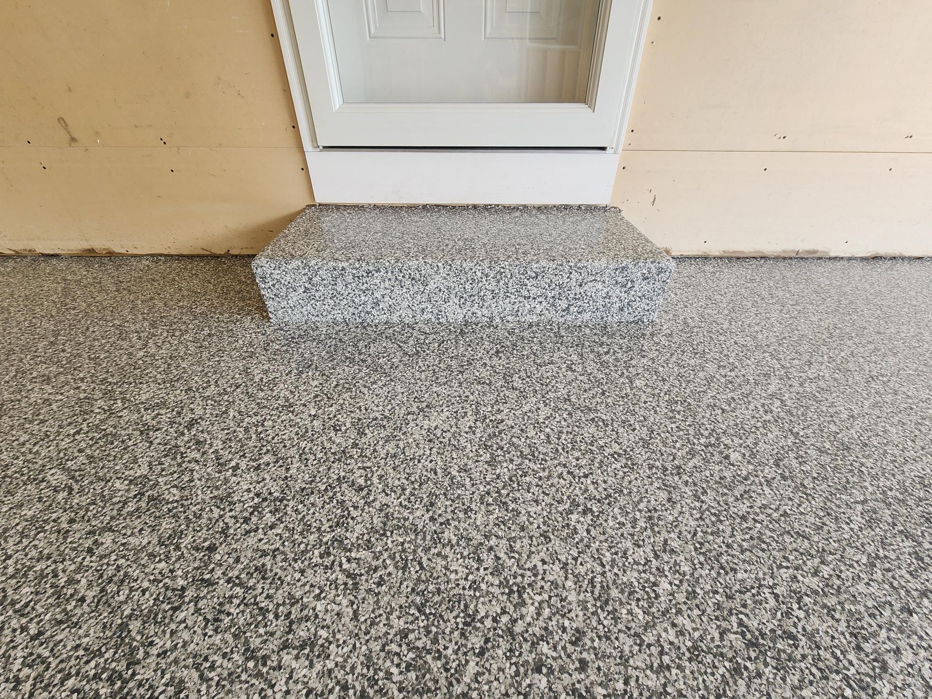 A close up of a garage floor with a door in the background.