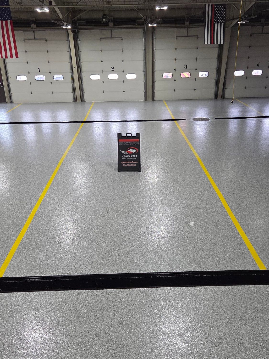 Empty warehouse floor with yellow lane markings and a small sign in the center.