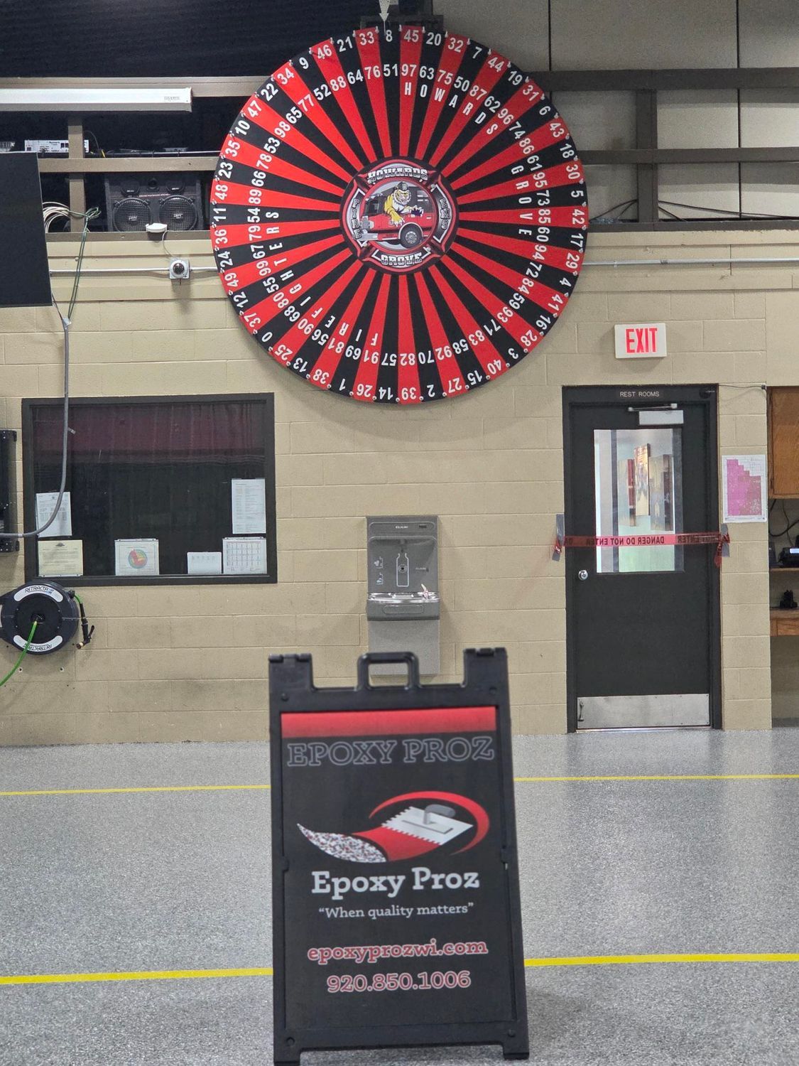 Indoor arcade wall with a large red-and-black prize wheel above an Epoxy Prox sign