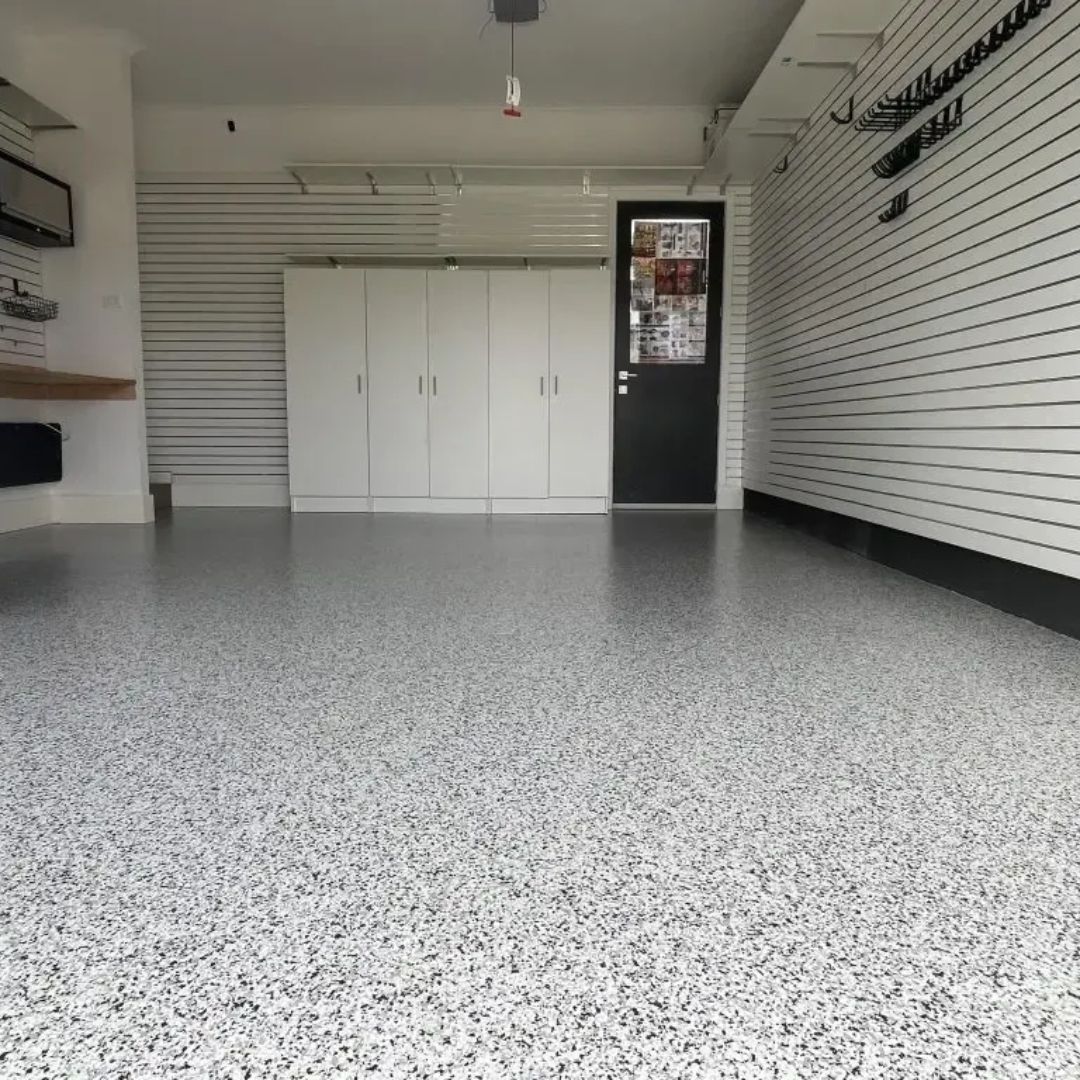 A garage with a white floor and a black door.