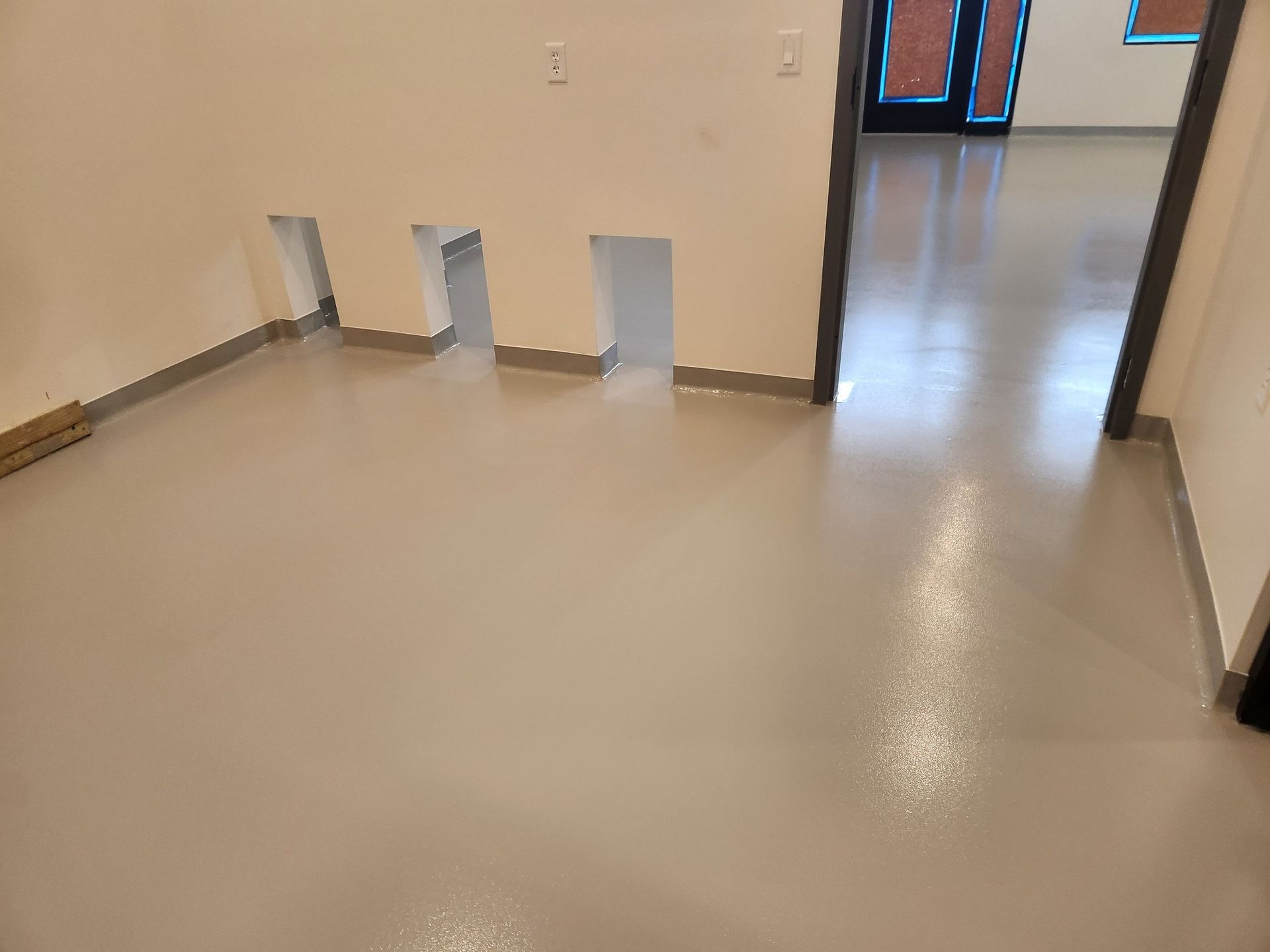 A room with a gray floor and white walls and a door.